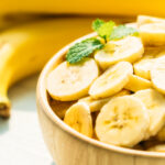 Raw yellow banana fruit slices in wooden bowl